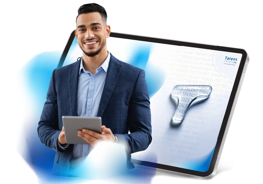 Un uomo sorridente con un tablet in mano si trova davanti a un'immagine di un tablet che mostra la prima pagina di Talent Trends.