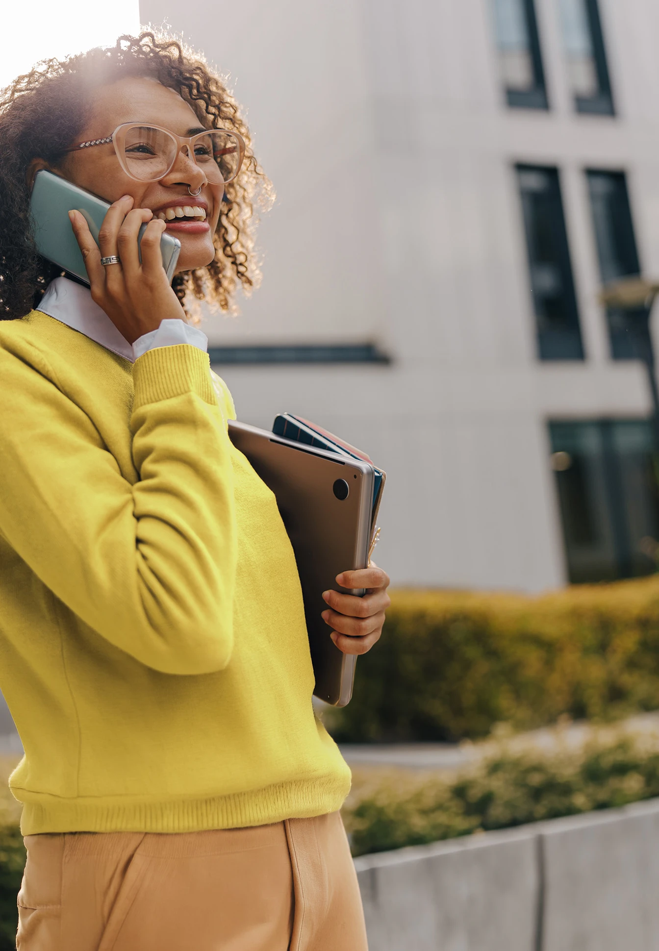 Una donna in abbigliamento da ufficio giallo mentre effettua una chiamata.