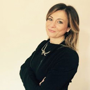 Persona sorridente con braccia incrociate, indossa abito nero.