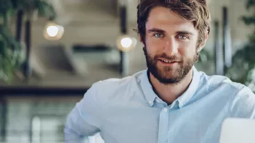 Persona sorridente in ufficio con laptop.