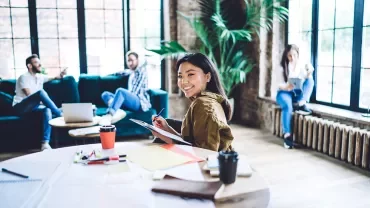 Persone in un ufficio moderno, una sorride verso la fotocamera.