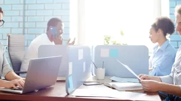 Persone sedute a lavorare su computer in un ufficio moderno.