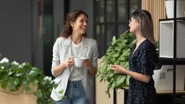 Due persone conversano sorridenti in un ambiente d'ufficio.