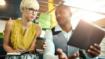 Due persone discutono in un ufficio, una con un tablet.