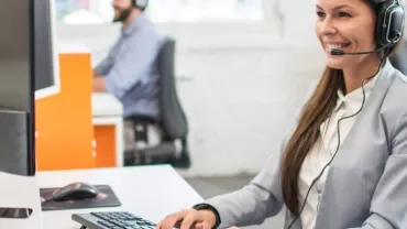 Operatore al computer con cuffie in un ufficio moderno.