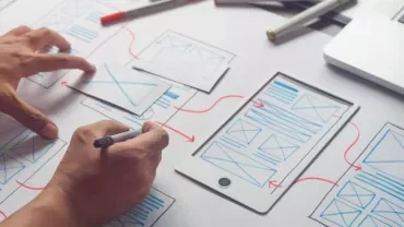 Persona che disegna un wireframe su un foglio con un tablet.
