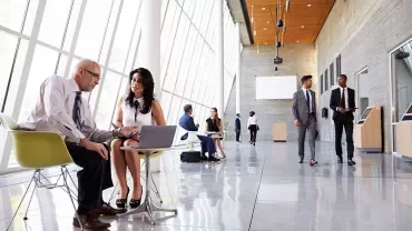 Persone in abiti formali in un moderno atrio ufficio.