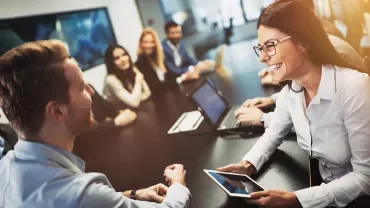 Riunione in ufficio con persone che sorridono attorno a un tavolo.