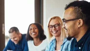 Gruppo di persone che sorridono durante una riunione.