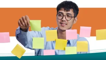 Persona con occhiali sistemando post-it colorati su un vetro.