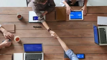 Vista dall'alto di persone che discutono e lavorano attorno a un tavolo in ufficio.