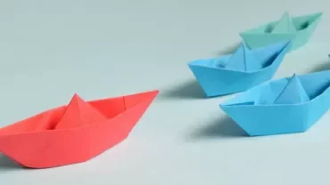 Barchette di carta colorate su sfondo chiaro.