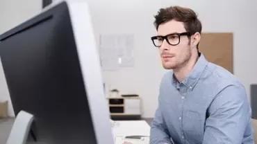 Persona seduta davanti a un computer che guarda lo schermo.