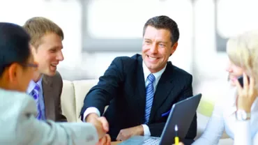 Persone in abiti formali si stringono la mano durante una riunione.