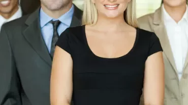 Gruppo di persone in abiti formali sorridenti.