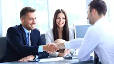 Colloquio di lavoro con stretta di mano in ufficio luminoso.