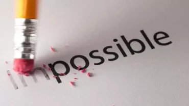Matita che cancella la parola 'impossible' su carta.