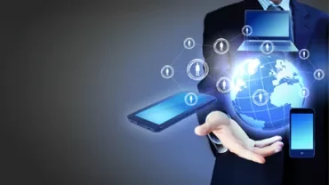 Persona in giacca con dispositivi digitali fluttuanti sopra una mano.