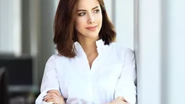 Persona in camicia bianca guarda fuori dalla finestra.
