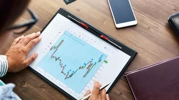 Persona che analizza un grafico finanziario su un tablet.