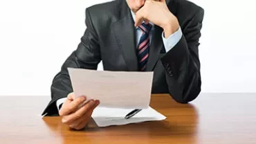 Persona in abito formale legge un documento.