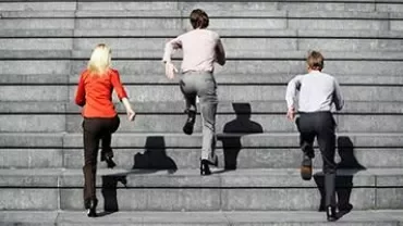 Tre persone che salgono scale in cemento all'aperto.