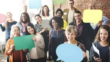 Persone che tengono cartelli colorati e sorridono.