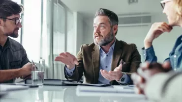Gruppo di persone che discute in riunione d'ufficio.