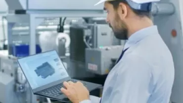 Ingegnere che lavora con un laptop in una fabbrica.