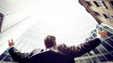 Persona in abito osserva un alto edificio moderno.