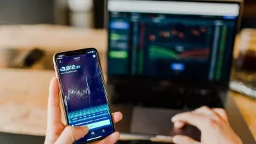 Smartphone e laptop con grafici di mercato.