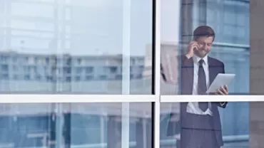 Persona in ufficio parla al telefono e usa un tablet.