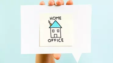 Mano tiene disegno con casa e scritta 'Home Office'.