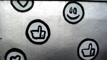 Murale con simboli di cuori e pollici su sfondo grigio.