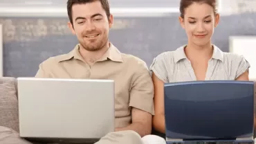 Due persone sedute con computer portatili.