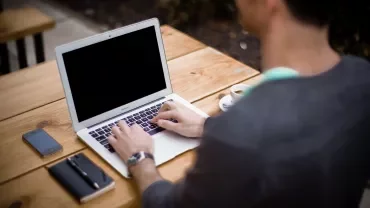 Persona al computer portatile in un caffè all'aperto.