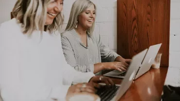 Persone lavorano insieme sui laptop al tavolo di legno.