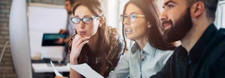 Gruppo di persone concentrate davanti a un computer alla scrivania.