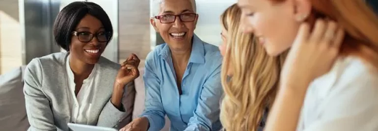 Gruppo di persone sorridenti in una conversazione, con un tablet.