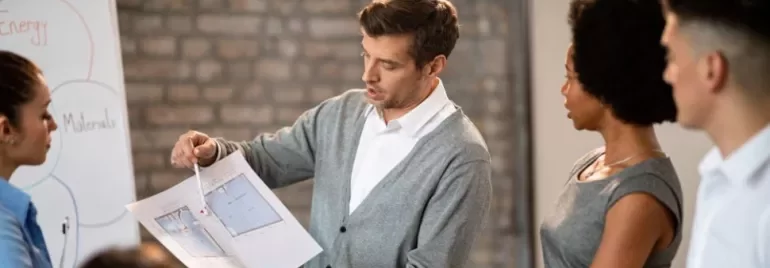 Persona spiega un progetto a un gruppo di colleghi durante una riunione.