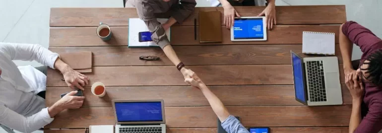 Vista dall'alto di persone che discutono e lavorano attorno a un tavolo in ufficio.