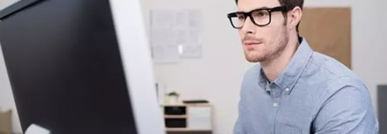 Persona seduta davanti a un computer che guarda lo schermo.