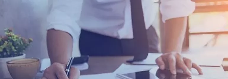 Persona che lavora su documenti con un tablet su un tavolo.