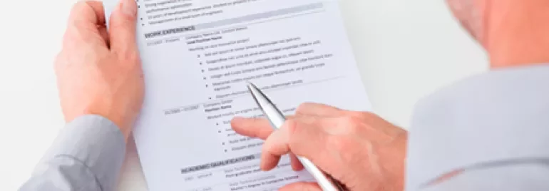 Persona che esamina un curriculum con penna in mano