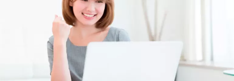 Persona sorridente davanti a un laptop con una tazza di tè sul tavolo.