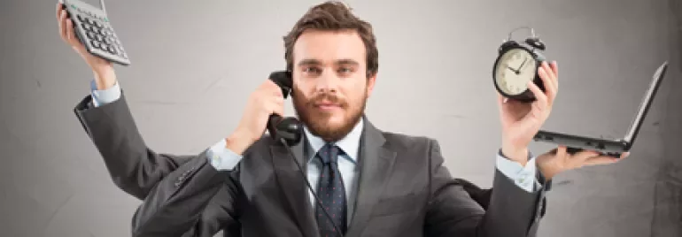 Persona multitasking con telefono, sveglia, calcolatrice e laptop.