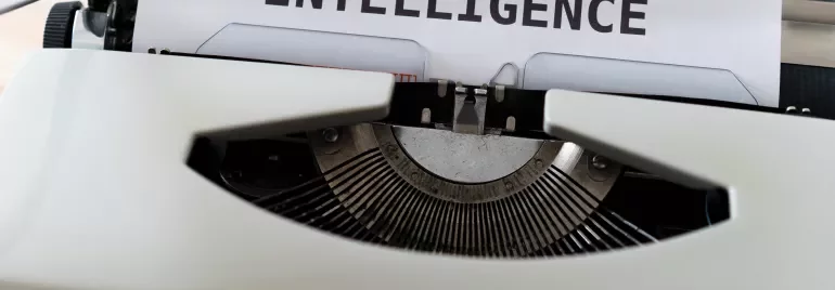 Macchina da scrivere con foglio che dice 'ARTIFICIAL INTELLIGENCE'.