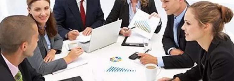 Riunione d'affari in ufficio con sei persone sedute attorno a un tavolo.