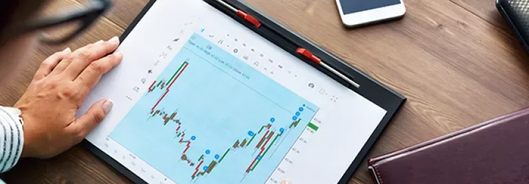 Persona che analizza un grafico finanziario su un tablet.