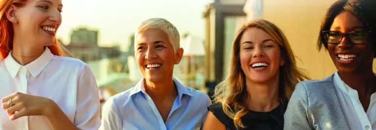 Gruppo di persone sorridenti con caffè all'aperto.